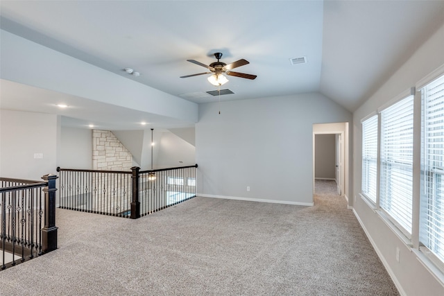 unfurnished room featuring baseboards, visible vents, ceiling fan, vaulted ceiling, and carpet flooring