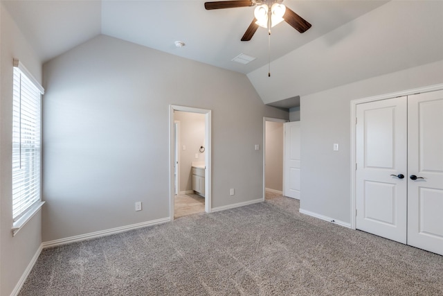 unfurnished bedroom with light carpet, a closet, baseboards, and vaulted ceiling