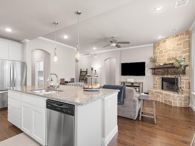 kitchen with arched walkways, stainless steel appliances, a sink, visible vents, and dark wood-style floors