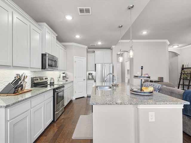 kitchen featuring arched walkways, a sink, visible vents, appliances with stainless steel finishes, and backsplash