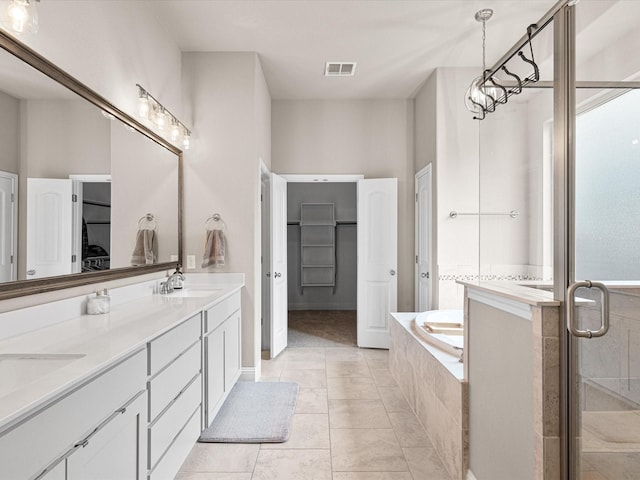 full bathroom featuring a garden tub, double vanity, visible vents, a spacious closet, and a sink