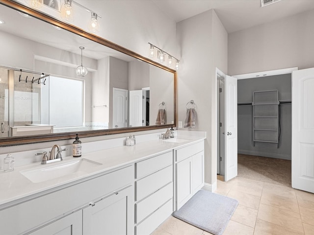 full bathroom with double vanity, a shower stall, a sink, and tile patterned floors