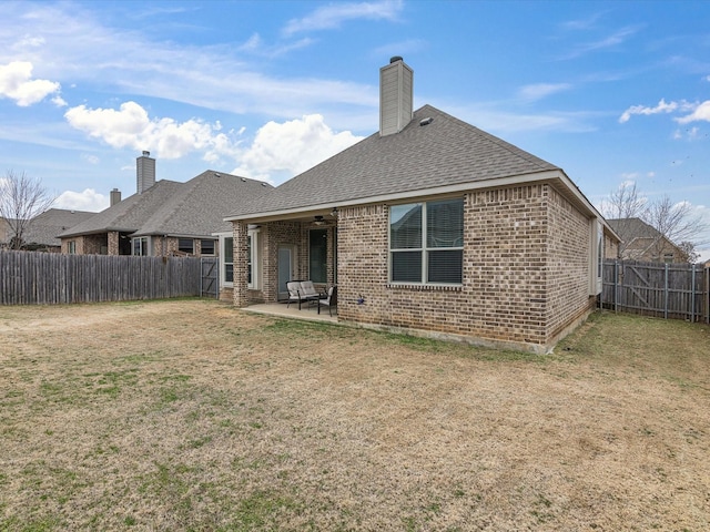 back of house with brick siding, a fenced backyard, a yard, and a patio