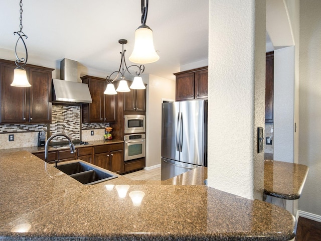 kitchen featuring tasteful backsplash, wall chimney range hood, dark brown cabinetry, stainless steel appliances, and a sink