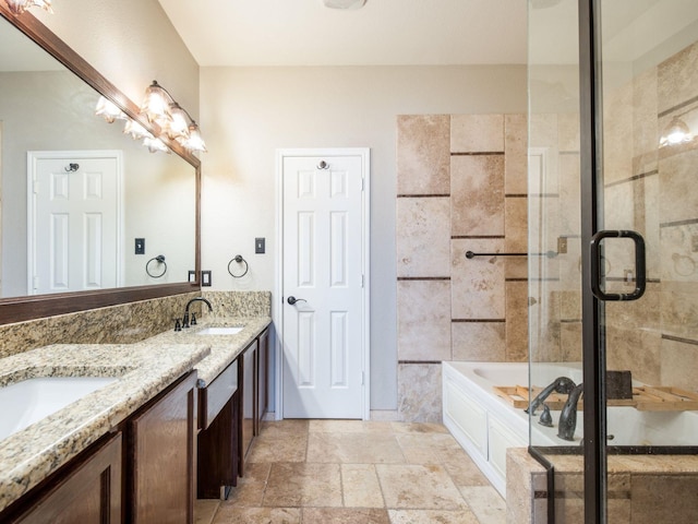 full bath featuring double vanity, stone tile floors, a stall shower, and a sink