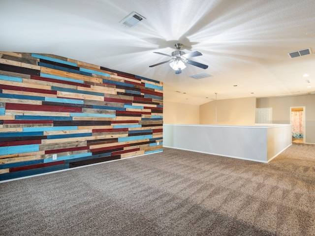 carpeted spare room featuring visible vents, an accent wall, and a ceiling fan