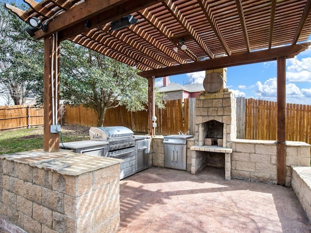 view of patio with fence, exterior kitchen, area for grilling, a pergola, and an outdoor stone fireplace