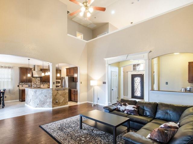 living room featuring baseboards, wood finished floors, arched walkways, and ceiling fan