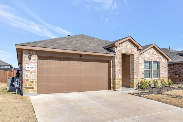 view of front of house with brick siding, central air condition unit, a shingled roof, a garage, and driveway