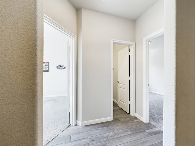 corridor with light wood-style floors and baseboards