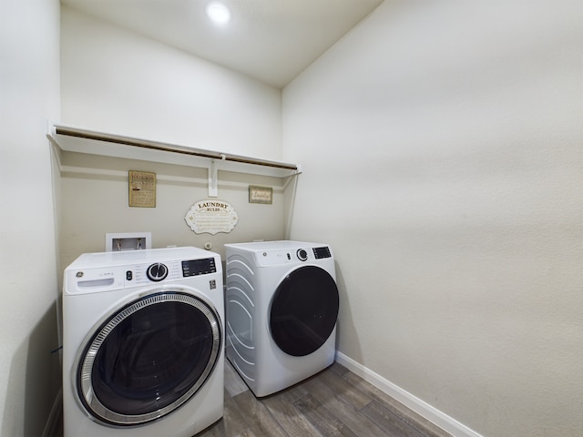 laundry area featuring laundry area, washing machine and dryer, baseboards, and dark wood finished floors