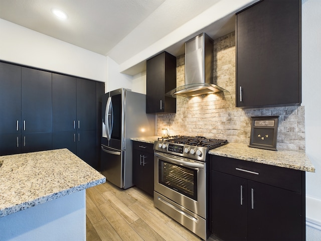 kitchen with tasteful backsplash, appliances with stainless steel finishes, modern cabinets, light wood-type flooring, and wall chimney exhaust hood