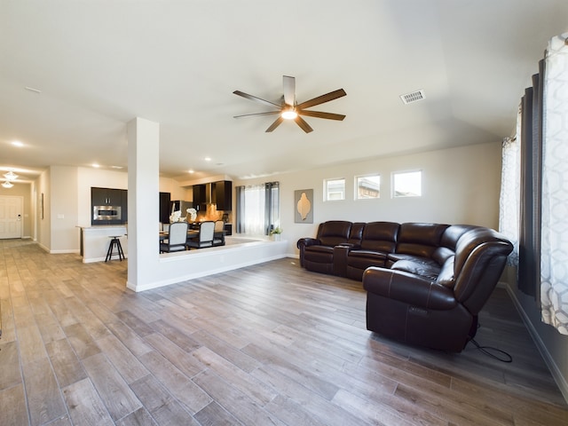 living room featuring visible vents, ceiling fan, baseboards, and wood finished floors