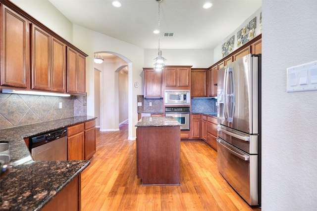 kitchen featuring arched walkways, appliances with stainless steel finishes, light wood-type flooring, and visible vents