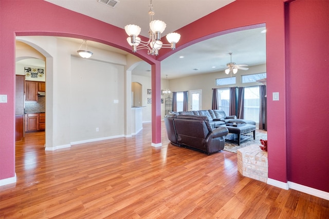 living area featuring light wood-style flooring, visible vents, arched walkways, and baseboards