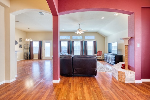 living area with light wood finished floors, baseboards, visible vents, lofted ceiling, and ceiling fan with notable chandelier