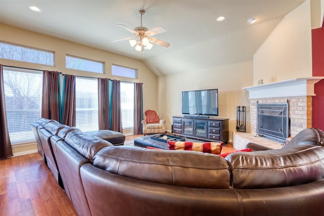 living room featuring lofted ceiling, recessed lighting, wood finished floors, a ceiling fan, and a brick fireplace