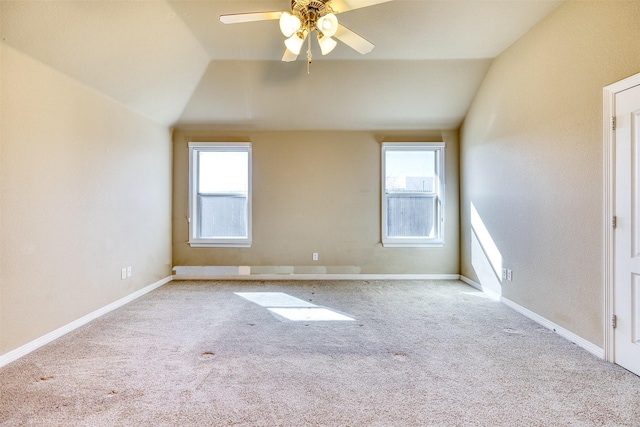 carpeted spare room featuring a wealth of natural light, vaulted ceiling, and baseboards