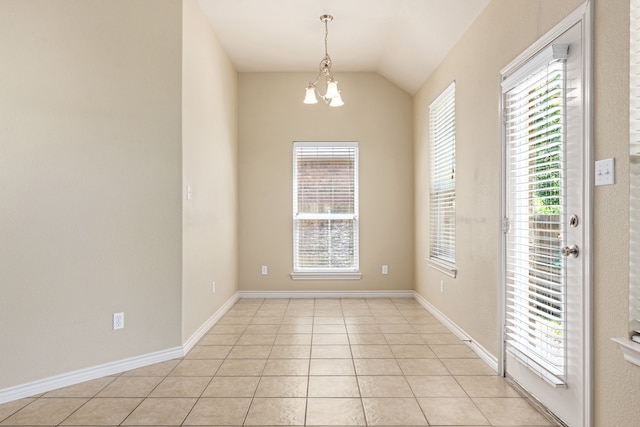 spare room with light tile patterned floors, vaulted ceiling, plenty of natural light, and an inviting chandelier