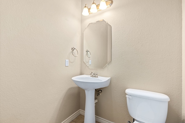 half bath with baseboards and toilet