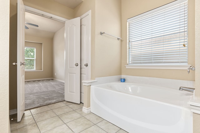 bathroom with tile patterned flooring, a bath, and baseboards