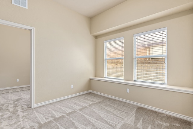 spare room with baseboards, visible vents, and light colored carpet