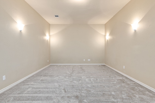 spare room featuring lofted ceiling, carpet floors, visible vents, and baseboards