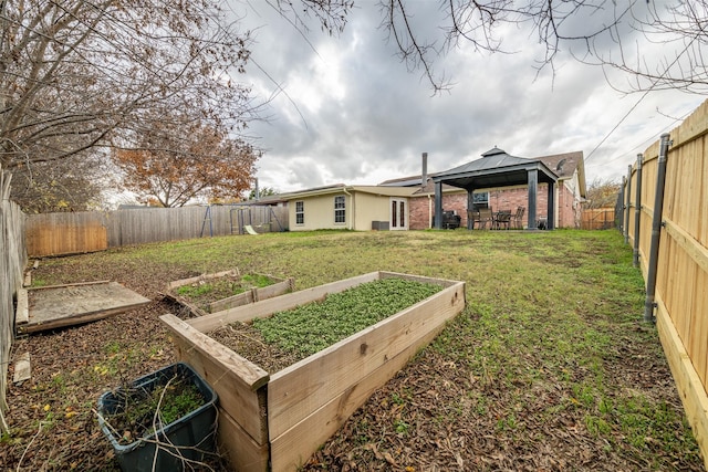 view of yard featuring a gazebo, a fenced backyard, and a garden