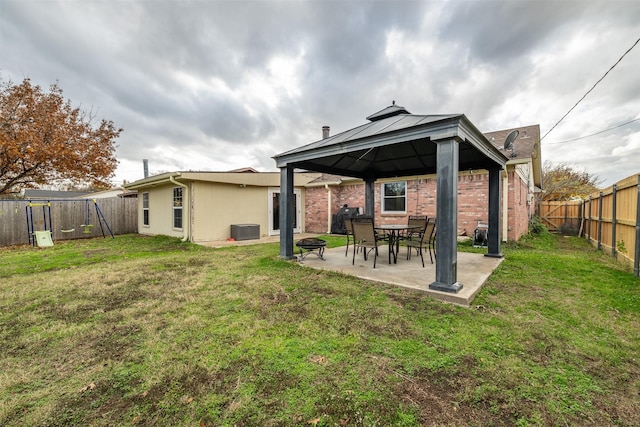 rear view of house featuring a fenced backyard, a gazebo, a yard, central air condition unit, and brick siding