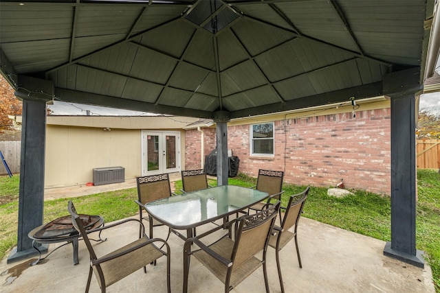 view of patio with outdoor dining space, fence, french doors, and a gazebo