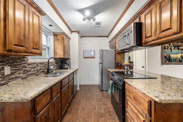 kitchen featuring stainless steel appliances, a sink, visible vents, ornamental molding, and dark wood-style floors