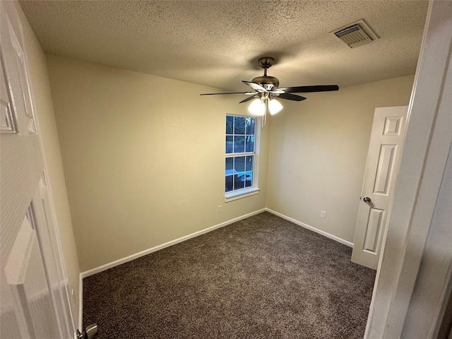 unfurnished bedroom featuring visible vents, dark carpet, a textured ceiling, and baseboards