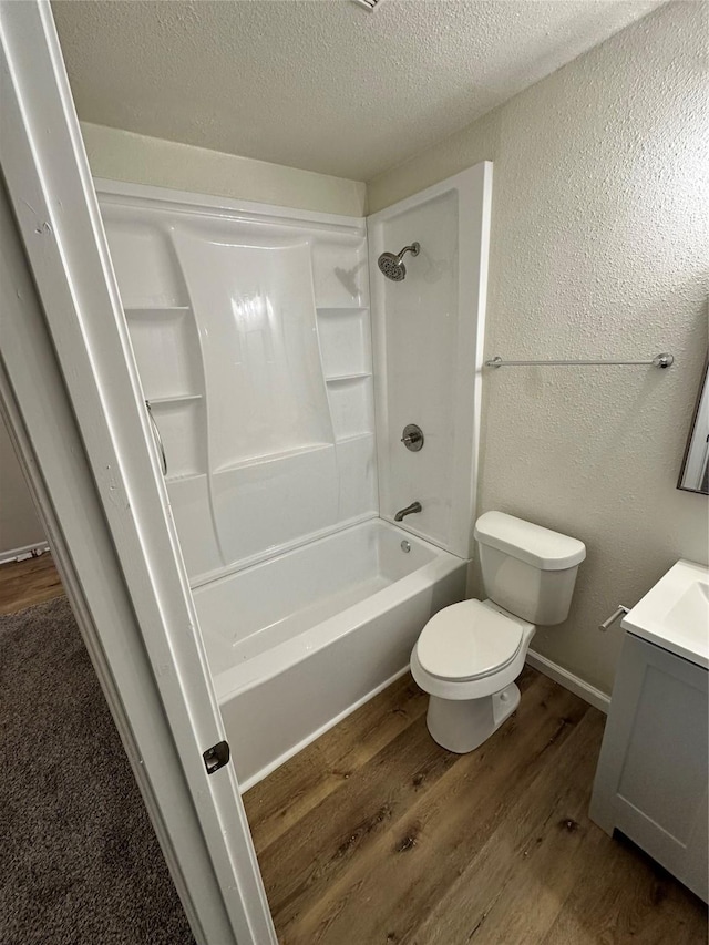 bathroom featuring a textured ceiling, a textured wall, toilet, wood finished floors, and vanity