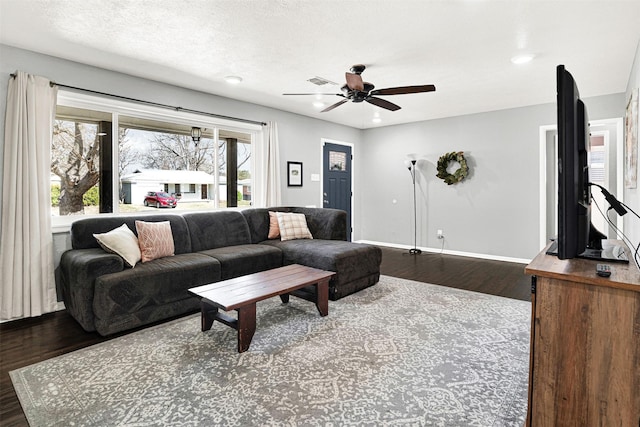 living area with visible vents, baseboards, a ceiling fan, wood finished floors, and a textured ceiling