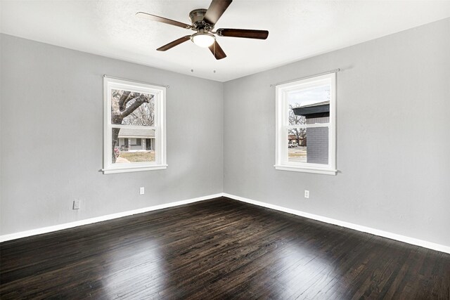 empty room featuring dark wood-type flooring, ceiling fan, and baseboards