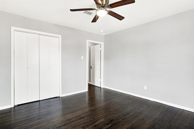 unfurnished bedroom featuring dark wood-type flooring, a closet, visible vents, and baseboards