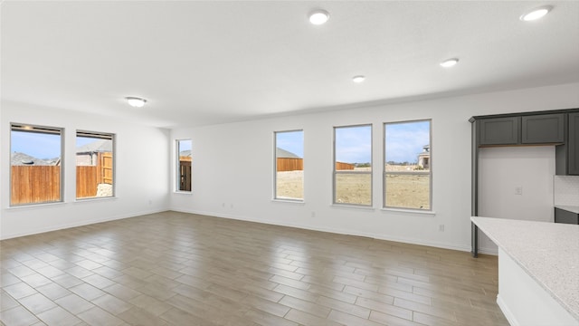 unfurnished living room featuring recessed lighting and baseboards