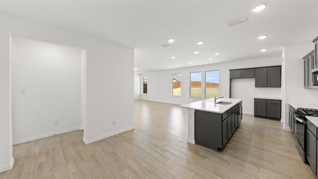 kitchen with visible vents, open floor plan, light countertops, a sink, and gas stove