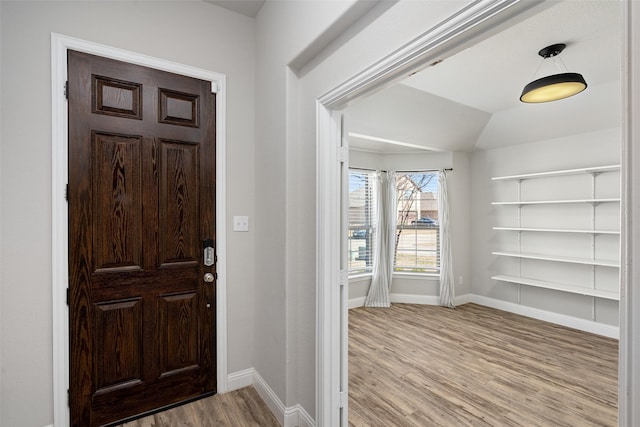 entryway with vaulted ceiling, light wood-style flooring, and baseboards