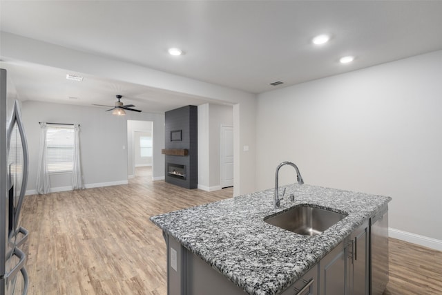 kitchen featuring a large fireplace, a sink, visible vents, light wood-style floors, and appliances with stainless steel finishes