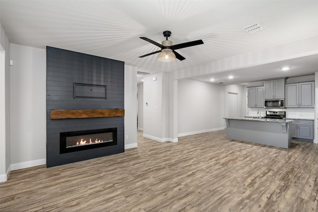 unfurnished living room with visible vents, a fireplace, light wood-style flooring, and baseboards