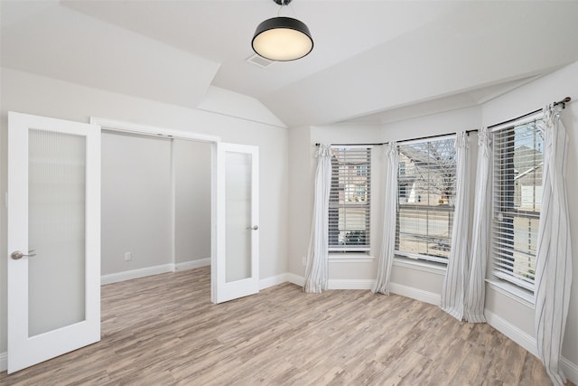 unfurnished bedroom featuring lofted ceiling, french doors, baseboards, and light wood finished floors