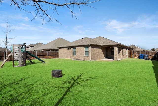 back of house featuring a fenced backyard, a lawn, and a fire pit