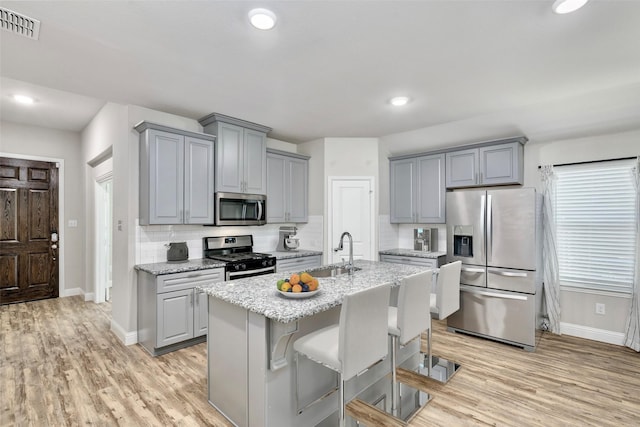 kitchen featuring stainless steel appliances, tasteful backsplash, visible vents, gray cabinetry, and a sink