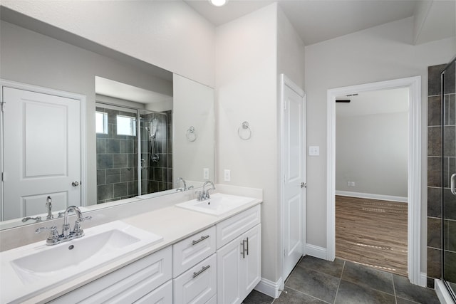 full bath with double vanity, a stall shower, a sink, and baseboards