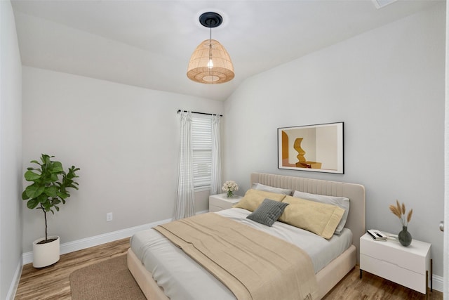 bedroom featuring baseboards, vaulted ceiling, and wood finished floors