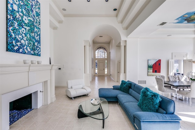 living room featuring arched walkways, a fireplace, visible vents, and crown molding