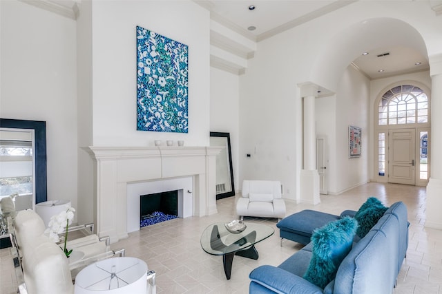 living area with arched walkways, a fireplace, crown molding, a high ceiling, and baseboards