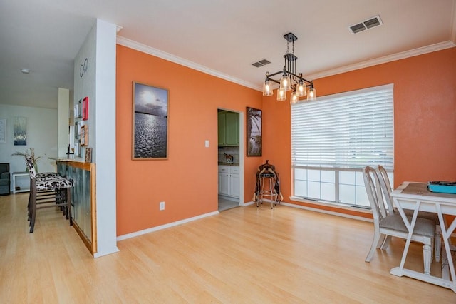 dining space with light wood-type flooring, visible vents, a chandelier, and ornamental molding