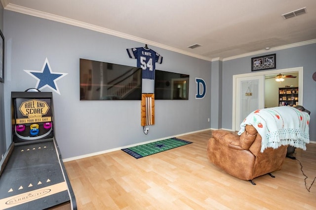 living area with ornamental molding, wood finished floors, visible vents, and baseboards